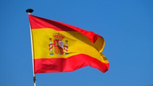 Bright Spanish flag waving against a clear blue sky, showcasing national pride.