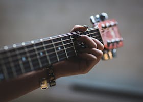 A musician's hand skillfully playing an acoustic guitar, focusing on the fretboard and strings.